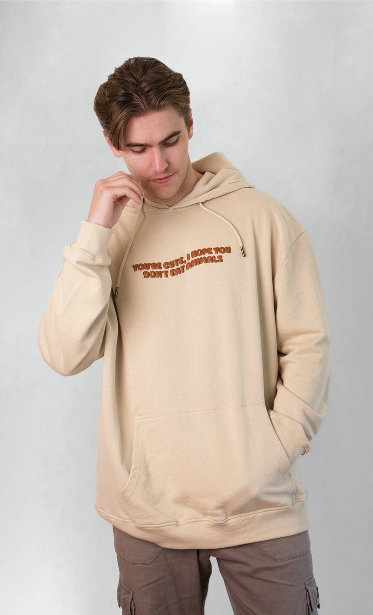 Beige hoodie with text worn by a person on a white background